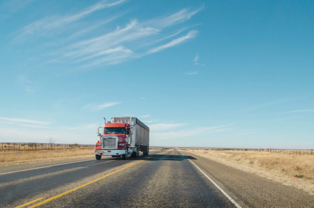 Red 18 wheeler travels down the highway