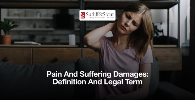 Person holding neck in discomfort on sofa with Sutliff & Stout logo and "Pain And Suffering Damages: Definition And Legal Term" text overlay